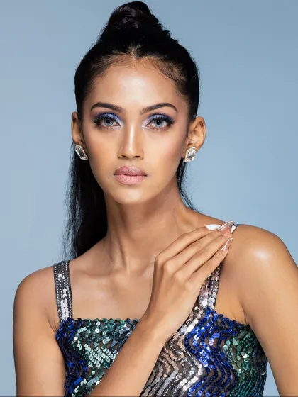 A classic beauty headshot with a direct gaze. The shot highlights the model's features, the precise makeup, and the elegant diamond stud earrings.