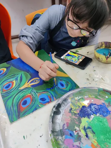 A young student paints a vibrant peacock, learning to blend the rich blues and greens of its feathers.