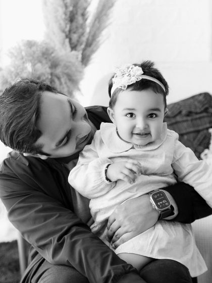 A father holds his baby girl in a tender black and white portrait.