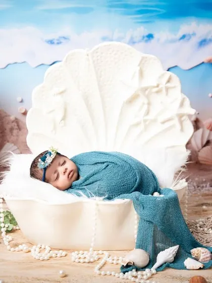 A creative ocean-themed photoshoot with the baby posed as a pearl in a large seashell. This demonstrates our ability to create elaborate, fantasy-inspired scenes for your little one's first portraits.