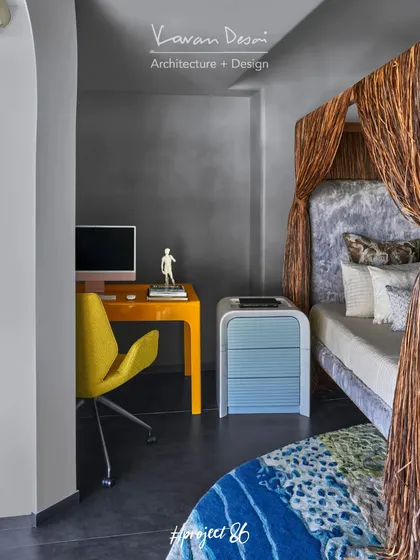 A detail of the study corner in the master bedroom, showing the vibrant yellow desk against the cool grey concrete-finish wall. The contrast of color and texture is a key theme throughout the project.