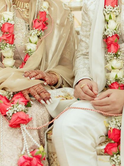 A close-up of the couple's hands and their beautiful red and white rose varmalas. This shot focuses on the symbolic details of their union.