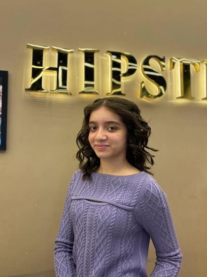 A cute and stylish look for a young client, with her hair styled in soft, face-framing curls.