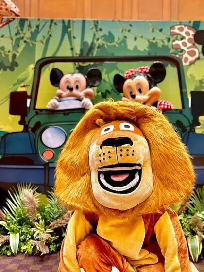 The whole gang is here! Mascots of Alex the Lion, Mickey, and Minnie pose in front of the safari jeep backdrop, creating a magical moment and an amazing photo opportunity.