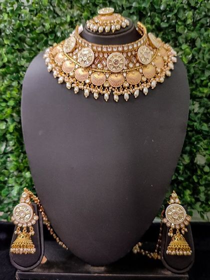 This classic temple coin necklace set, available for purchase, is perfect for creating an authentic South Indian bridal look. The set includes a choker, earrings, and a maang tikka.