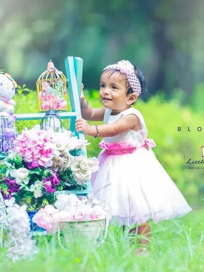 A blossoming personality. The vibrant green grass and soft floral colors create a fresh, beautiful backdrop for this little one's portrait.