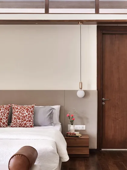 A detail of the custom bed in 'A Walk in the Clouds', with an upholstered headboard and a sleek wooden side table.
