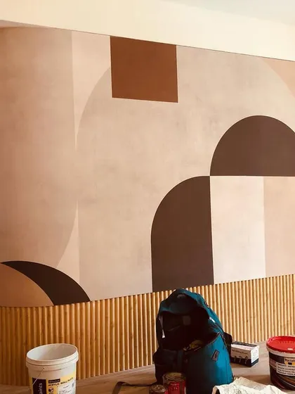 This image shows a large, abstract geometric mural being installed on a curved wall. I carefully wrap the design around corners to maintain a continuous, seamless look.