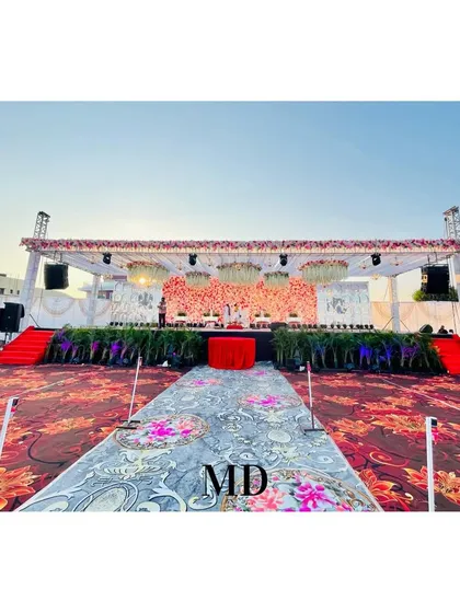 A wide shot of the grand floral wedding stage and the expansive seating area. We designed the layout to ensure all guests have a clear view, with a custom-printed aisle runner leading to the main stage.