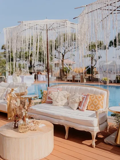 A closer look at the poolside lounge seating, featuring elegant cabriole-leg sofas and macrame umbrellas. The mix of textures adds depth and interest to the decor.