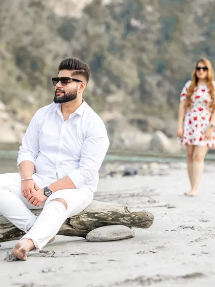 A beautifully composed shot with the groom in the foreground and the bride in the background, creating depth and interest in this riverside pre-wedding photo.