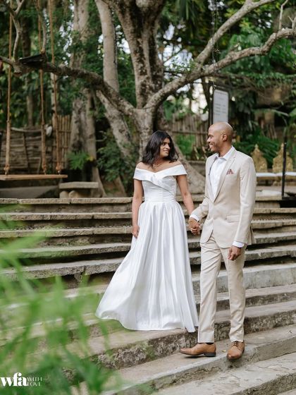 A couple dressed in elegant western attire walks down the stone steps by the Kalyani, a beautiful pre-wedding photo.