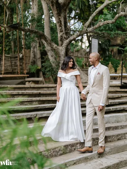 A couple in modern wedding attire walks down the stone steps, showcasing the venue's suitability for both traditional and contemporary celebrations.