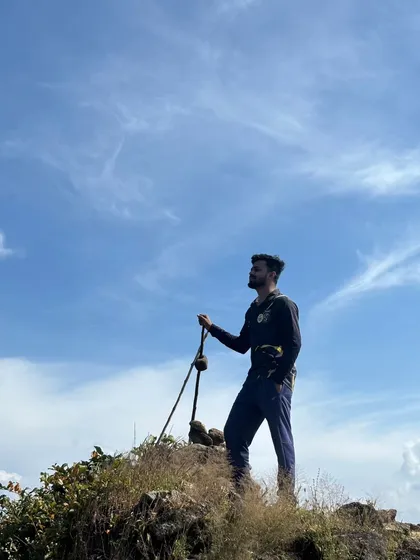 Standing tall at the peak. A trekker with a walking stick at the summit of Narasimha Parvatha.