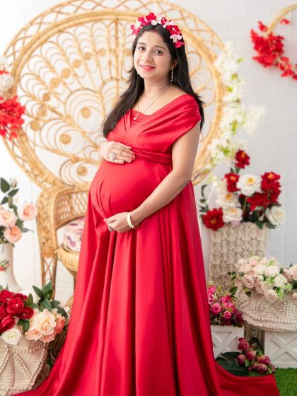 Radiant in red. This portrait captures the mother-to-be in a beautiful red gown, surrounded by floral arrangements in our boho-inspired studio setup. The floral crown adds a touch of softness to the bold look.