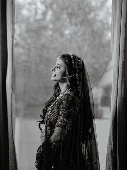 A timeless black and white portrait of the bride by a window. The natural light and her serene expression create a classic, poetic image.
