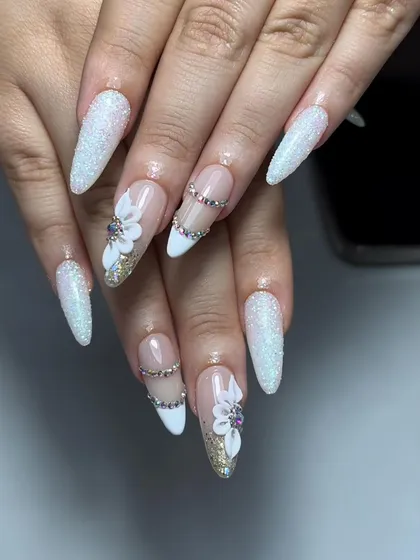 A truly show-stopping set of stiletto nails. The design includes a mix of glitter, 3D flowers, and chains of rhinestones for a high-glam, bridal look.
