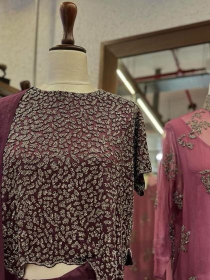A close-up of a crop top with all-over silver embellishments, paired with a matching skirt and sheer dupatta.