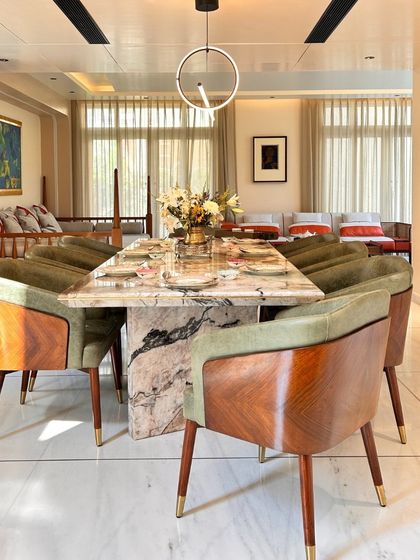 The dining space in the Palm Springs Villa is centered around a stunning marble table. We paired it with elegant wood and green upholstered chairs to create a connection with nature, making it a perfect setting for shared meals.