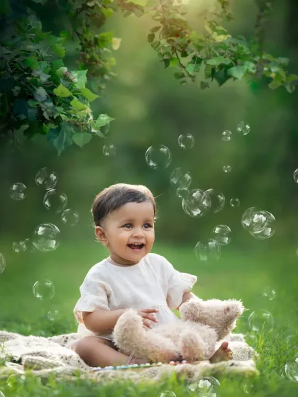 The pure joy of a baby surrounded by bubbles in a beautiful park setting. This is a perfect shot for a one-year-old baby photoshoot.