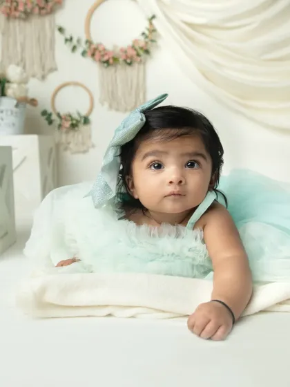 A lovely shot of an infant during tummy time. The soft, neutral background with boho-chic details keeps the focus on her beautiful, curious eyes.