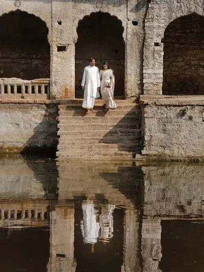 A stunning reflection shot at a historic stepwell, creating a perfectly symmetrical and timeless pre-wedding portrait.