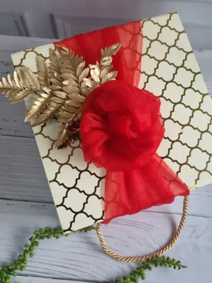 A beautifully wrapped gift bag with a golden floral accent, perfect for elevating your corporate gifting and making a lasting impression.