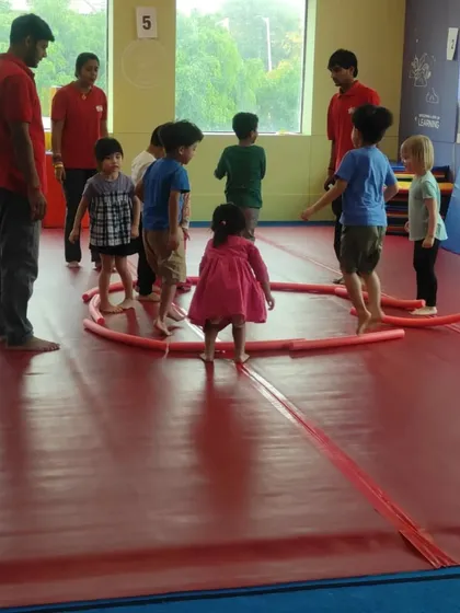 A group of preschoolers plays a game with pool noodles, a fun activity that promotes movement, listening, and following directions.