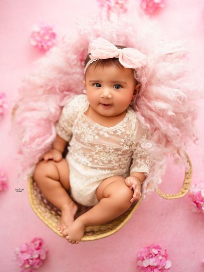 A sweet portrait of this baby girl sitting in a teacup, surrounded by pink fluff and flowers.