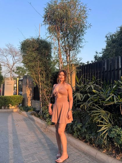 A sun-kissed shot in a dusty pink halter mini dress, perfect for a warm afternoon.