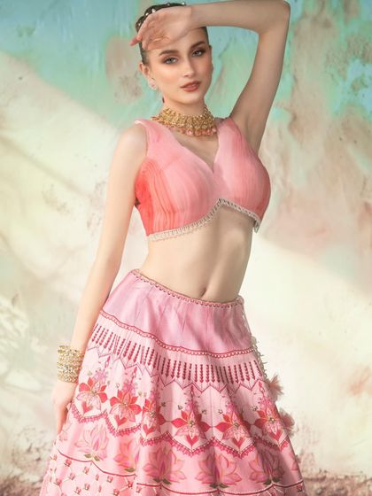 A mesmerizing backdrop created by projection sets a soft, pastel scene. The lighting is designed to complement the delicate colors of the lehenga, creating a dreamy and elegant portrait.