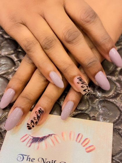 A duplicate of image 242, showing an elegant design on long almond nails. The mauve base is complemented by accent nails with intricate black hand-painted patterns.