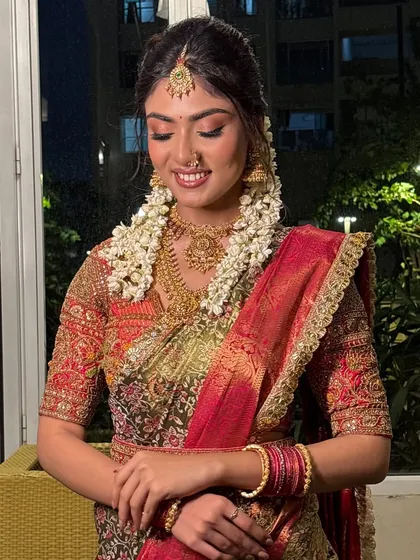 The bride looking down, showcasing her beautiful makeup and the traditional jasmine flowers in her hair.