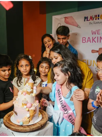 The birthday girl, surrounded by her friends, cuts her beautiful ice-cream-themed cake after a fun-filled baking party.