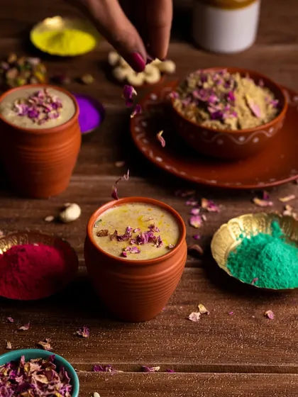 An action shot of rose petals being sprinkled over the Thandai. This adds a dynamic element to the still photograph, making it feel more alive.