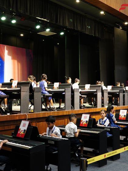 This is what a fully integrated music program looks like. Dozens of students are seated at their individual keyboards during an annual recital, demonstrating the scale and ambition of our in-school music labs.