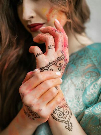 A close-up on hands adorned with henna and stained with Holi colors, symbolizing the beautiful mess of love and celebration.