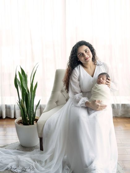 A full-length portrait of a mother in a beautiful white dress, holding her newborn. An elegant and timeless image.