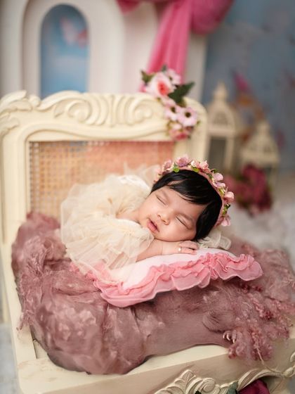 The soft textures of lace and tulle create a dreamy atmosphere for this sleeping baby girl, adorned with a floral headband.