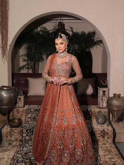 The full picture of a modern maharani. This rust-toned bridal outfit is paired with makeup that is both regal and contemporary, perfect for the bride who walks her own path.