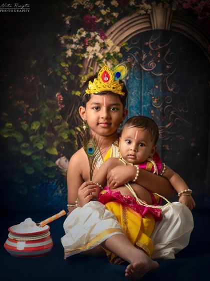 A baby boy portrayed as the infant Krishna, complete with pearl necklaces and a pot of white butter, showcasing a classic and adorable theme.