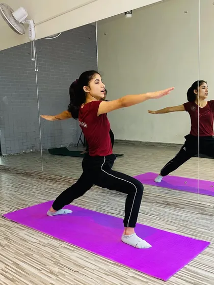The Warrior II pose (Virabhadrasana II) is fundamental in yoga for building stamina and concentration. Here's a student holding the pose with strength and focus in front of the mirror, helping her check her alignment.