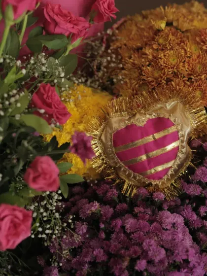 A detailed shot of the floral decor, featuring a handcrafted heart-shaped ornament in rani pink and gold, nestled among fresh blooms.