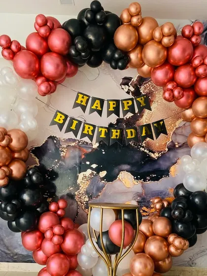 A bold and modern birthday backdrop featuring a balloon ring in black, white, and metallic pink against a marble-print background.