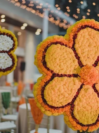 Large floral installations in the shape of flowers, made entirely from marigolds and other traditional blooms. A creative and impactful decor piece for the Mata ki Chowki.