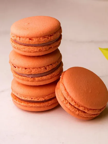 A stack of lovely orange-coloured macarons. These delicate French cookies are a perfect, light treat for any time of day.