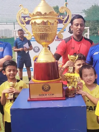 The team celebrating with a large gold cup. These victories are a testament to their hard work and the support of their coaches and families.