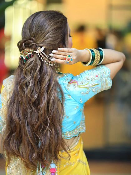 A back view of a stunning half updo with soft, beachy waves. The colorful hair accessory adds a beautiful pop of color to the look.