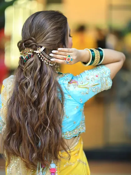 A back view of a stunning half updo with soft, beachy waves. The colorful hair accessory adds a beautiful pop of color to the look.