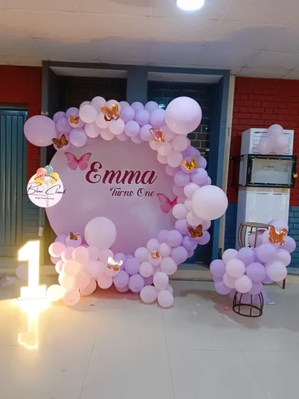 A dreamy butterfly-themed first birthday with a custom backdrop and a pastel purple balloon garland.